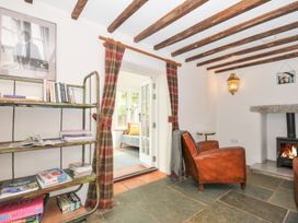 A living room with a chair and a bookshelf at Rose Cottage Okehampton