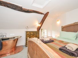 A bedroom with a bathtub and bed at Rose Cottage in Okehampton