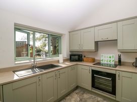 A kitchen with a sink, windows, microwave, and cabinets at Bottom Lodge in Penhow