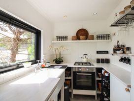 A kitchen with a stove, sink, and shelves at West Island in Kingsbridge
