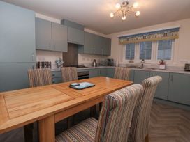 A kitchen with blue cabinets a wooden dining table and striped chairs at Happy Days in Bridlington