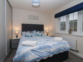 A bedroom with a double bed with blue and white bedding and pillows with coral designs with bedside tables and lamps at Happy Days in Bridlington