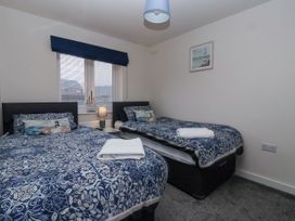 A bedroom with two single beds with blue patterned bedding and a window with blinds at Happy Days in Bridlington