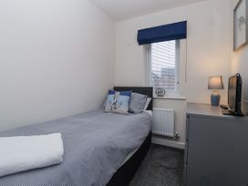 A small bedroom with a single bed a window a dresser a lamp and a television at Happy Days Bridlington
