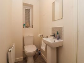 A small bathroom with a toilet sink mirror and window ledge with decorations at Happy Days in Bridlington