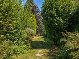 A pathway through greenery with a bench in the garden at The Mews in Blisland