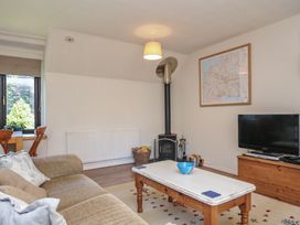 A living room with a television and wood stove at The Mews in Blisland