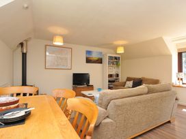 A living room with a dining table and television at The Mews in Blisland