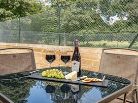 A table with wine glasses, wine bottle, grapes, cheese, and crackers in an outdoor area at The Annex in Wimborne Minster