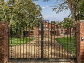A gated entrance with a gravel driveway and a house in the background at The Annex in Wimborne Minster