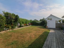 A garden with flower beds and a shed at Trem Ynys in Mynytho near Abersoch