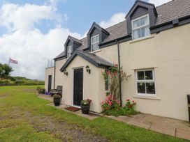 A house with a black door and flowers in planters at North Studdock Cottage, Angle near Pembroke