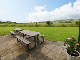 A table and benches on a patio area at North Studdock Cottage in Angle near Pembroke