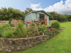 A garden with a green cottage and plants at North Studdock Cottage Angle near Pembroke