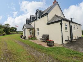 An outdoor view of a house with a bench and flower pots at North Studdock Cottage Angle near Pembroke