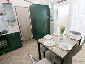A kitchen with a dining table and chairs at Oyster Lodge in Little Haven