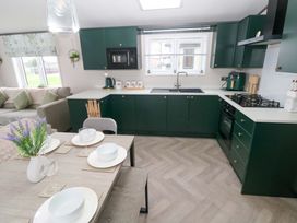 A kitchen with cabinets and dining table at Oyster Lodge Little Haven