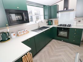 A kitchen with cabinets, sink, stove, and microwave at Oyster Lodge Little Haven