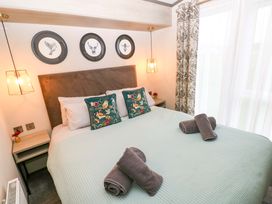 A bedroom with a bed and wall art at Oyster Lodge in Little Haven