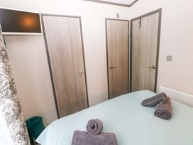 A bedroom with a bed and towels at Oyster Lodge in Little Haven