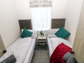 A bedroom with twin beds and a bedside table at Oyster Lodge in Little Haven