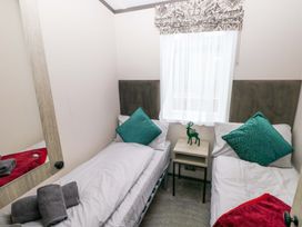 A bedroom with two beds and a side table at Oyster Lodge in Little Haven