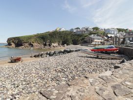 A beach with boats on pebbles and houses on a hill at Ocean House in Broad Haven