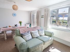A living room with a green sofa and dining table with flowers at The Seaside Inn in Beer