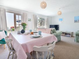 A dining table with place settings and flowers in a living room with sofas and a television at The Seaside Inn in Beer