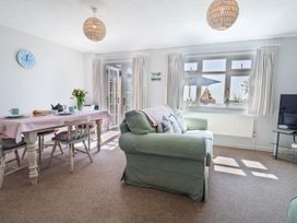 A living room with a green sofa and a dining table set for breakfast at The Seaside Inn in Beer