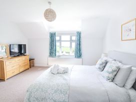 A bedroom with a bed pillows and folded towels a dresser with a TV and a window with curtains at The Seaside Inn in Beer