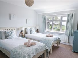 A bedroom with two single beds side by side each with a pillow lamp and rolled towels at The Seaside Inn in Beer
