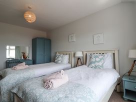 A bedroom with two single beds dressers with mirrors lamps and a wardrobe at The Seaside Inn in Beer