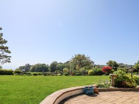 A garden with green grass shrubs and trees under a clear sky at The Seaside Inn in Beer
