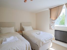 A bedroom with two single beds a nightstand between the beds and a window with curtains at Fig Tree House in Axminster