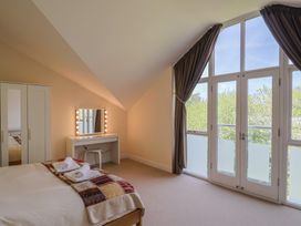A bedroom with a bed a wardrobe and a vanity table near large windows at Fig Tree House in Axminster