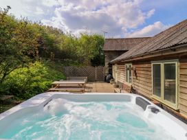 An outdoor patio with a hot tub picnic table bench and wooden building at Waldegrave Barn Hartest near Glemsford