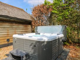 An outdoor hot tub with steps next to a wooden building and trees at Waldegrave Barn Hartest near Glemsford