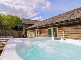 An outdoor hot tub with bubbling water next to a wooden building with a sloped roof at Waldegrave Barn Hartest near Glemsford