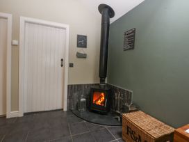 A living room with a wood stove and a clock at The Old Tannery Beaumaris