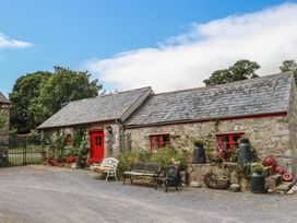 A cottage with a red door, benches, and flower pots at The Dairy in Ardfinnan, County Tipperary