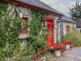 A cottage exterior with stone walls and red flowers at The Dairy in Ardfinnan, County Tipperary