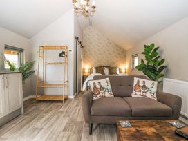A bedroom with a bed, sofa with duck pillows, wooden shelving, plants and a chandelier at Duck Lodge in Bedale