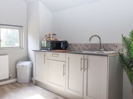 A kitchen area with cabinets a sink microwave kettle and a trash bin at Duck Lodge in Bedale