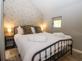 A bedroom with a metal frame bed two bedside tables with lamps and a small window at Duck Lodge in Bedale