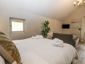 A bedroom with a bed white towels a brown sofa a small window a plant and a wall mounted television at Duck Lodge in Bedale
