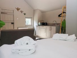 A bedroom with a bed and folded towels a sofa kitchen cabinets and a small window at Duck Lodge in Bedale