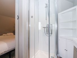 A bathroom with a glass shower enclosure and white storage cabinet next to a bedroom at Duck Lodge in Bedale