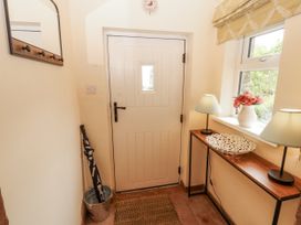 A hallway with a door, table, lamps, and flowers at White House in Shap