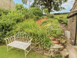 A garden with stone stairs and a white bench at White House in Shap